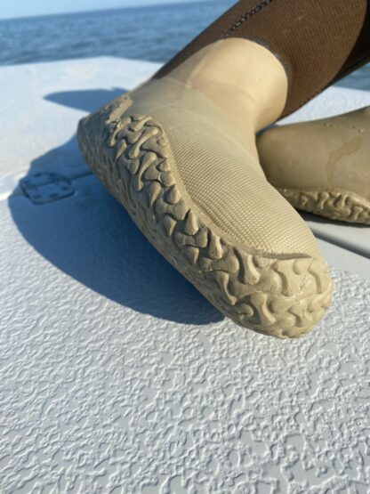 A person wearing beige shoes on top of a white surface.